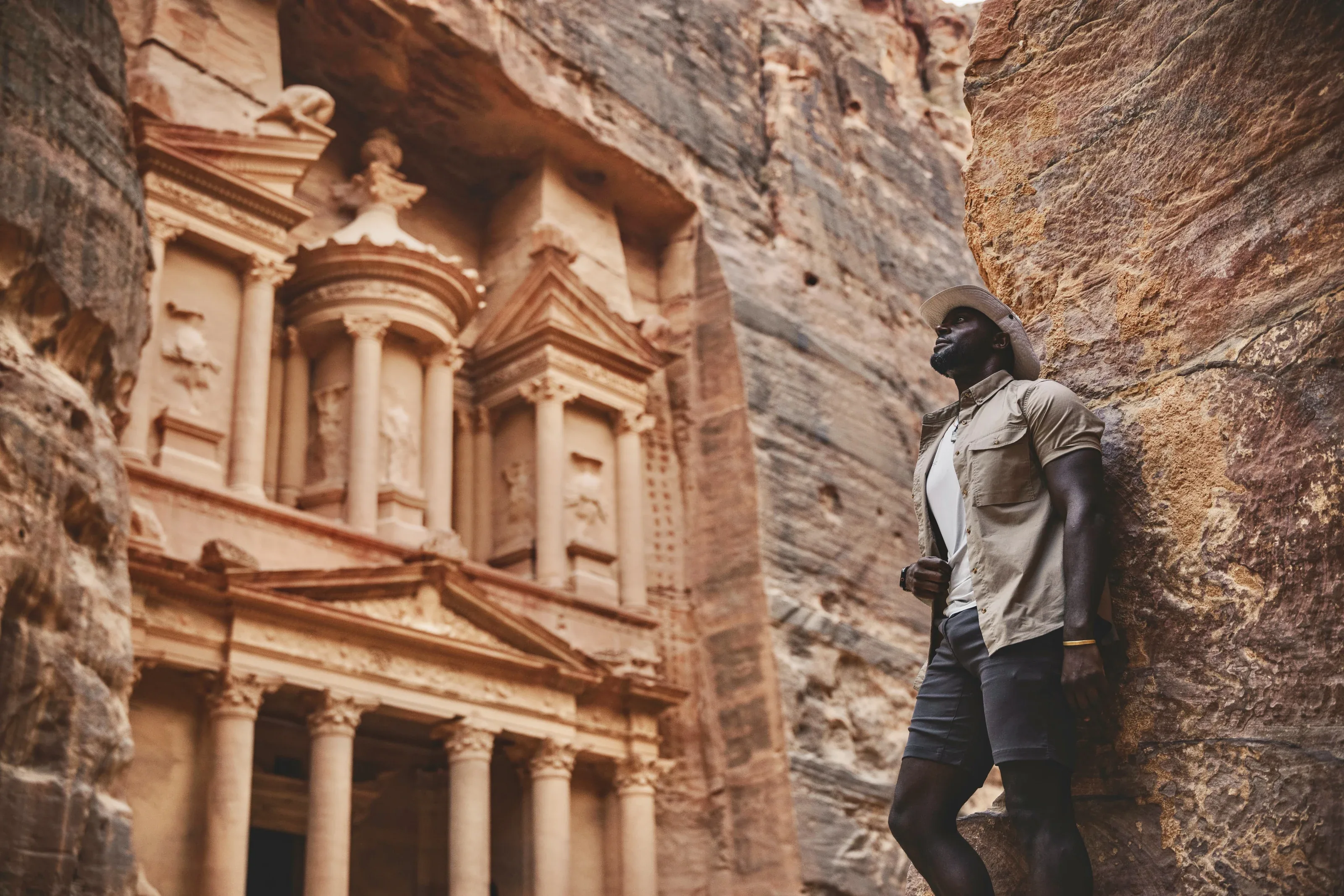 Mario Rigby standing beside sandstone cliffs and an ornate stone façade.