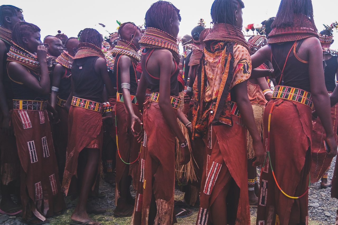 A line of dancers in red ochre and beads