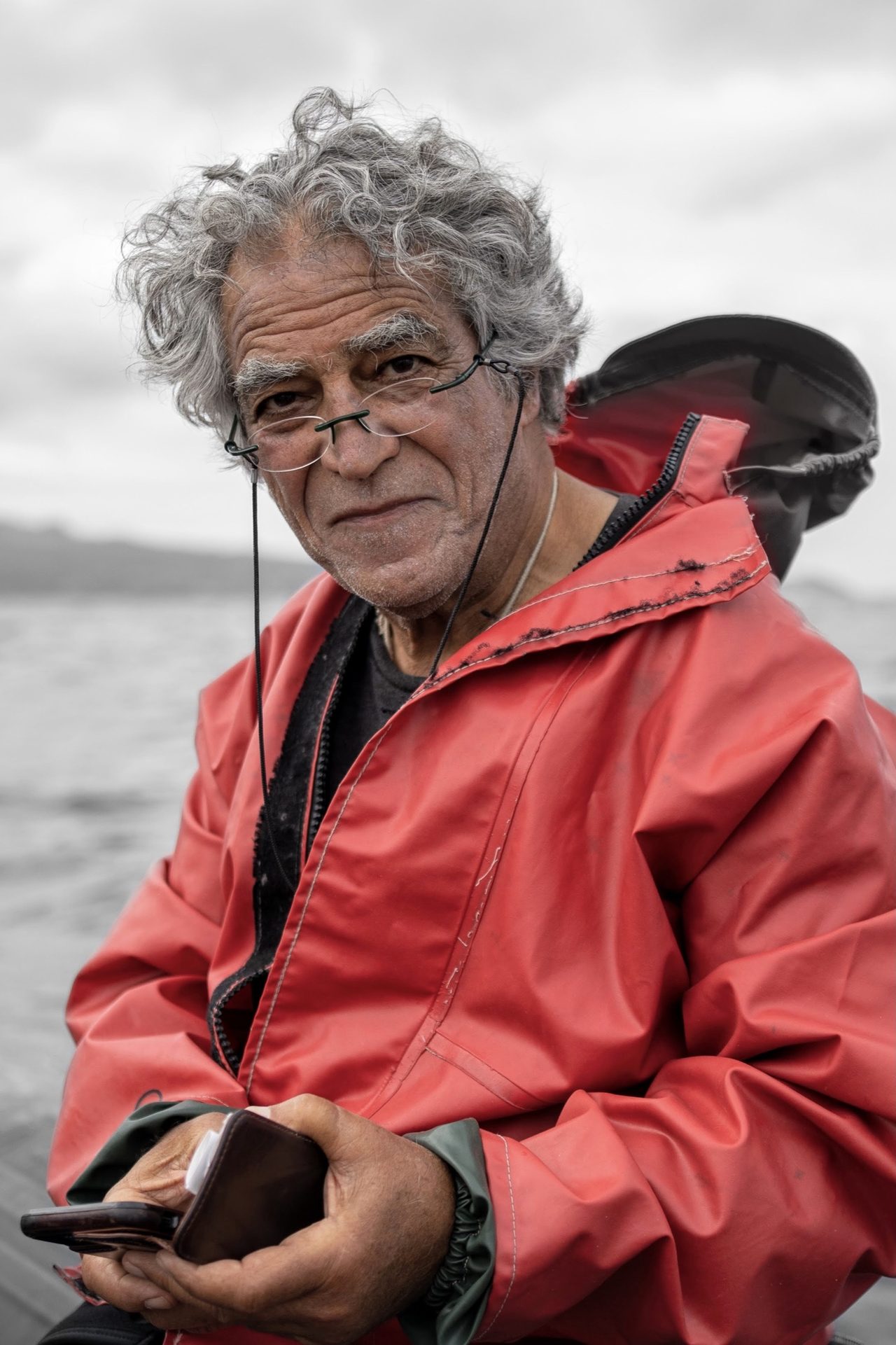 An older man with grey curls in a red rain jacket