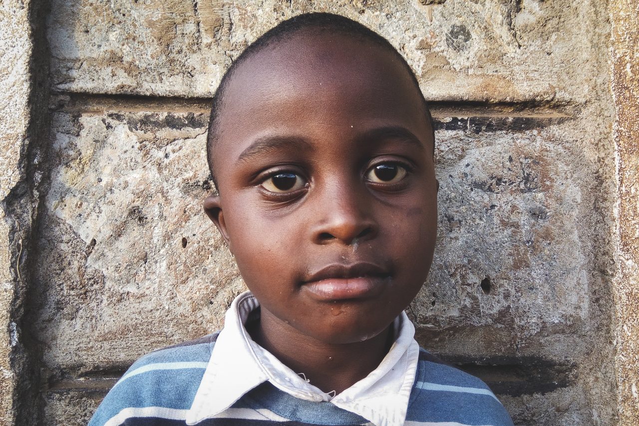Close portrait of a young boy against a stone wall